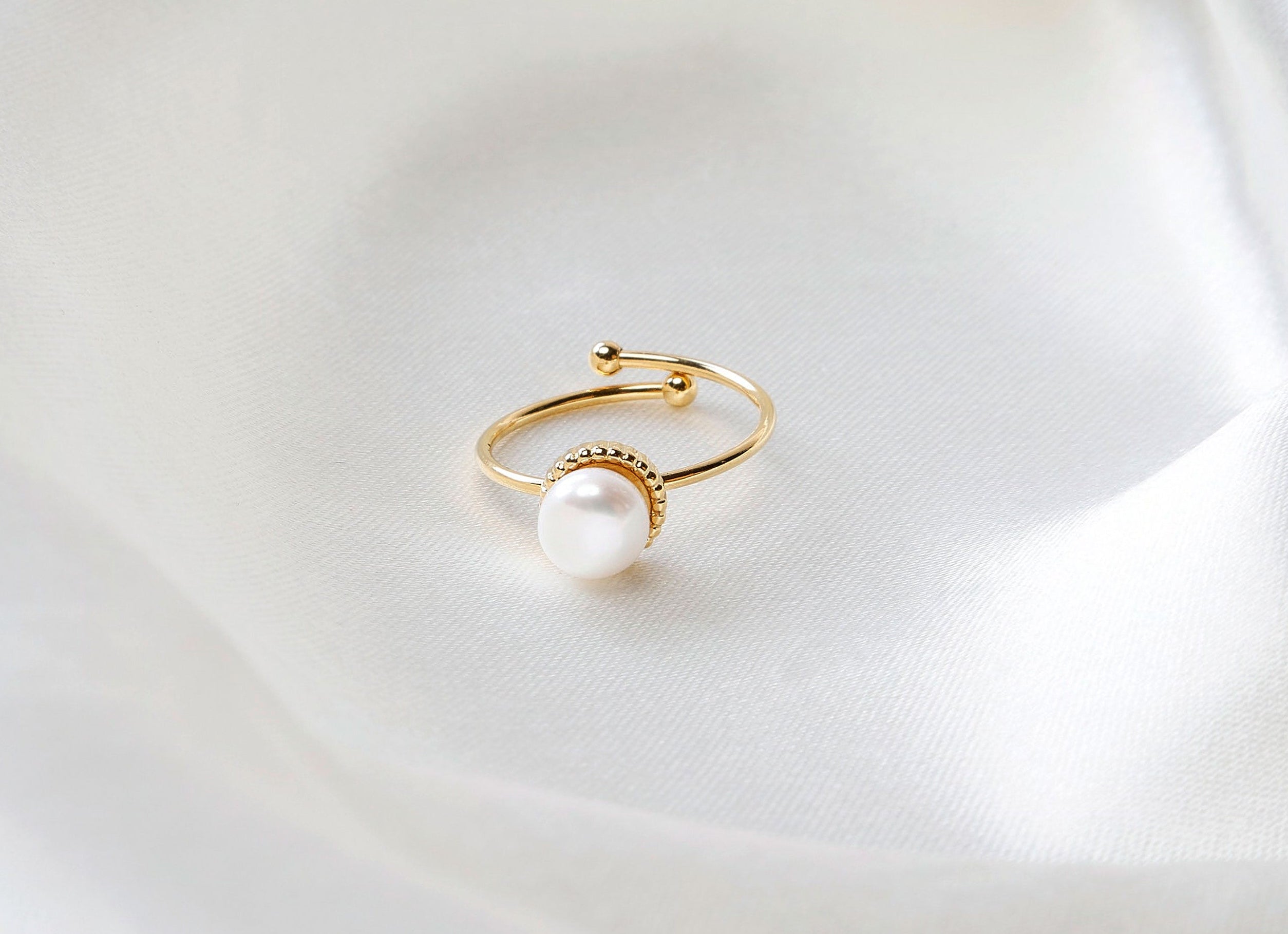 Gold ring with a pearl on a white fabric background