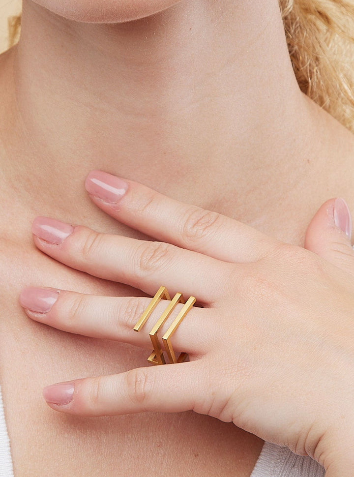Woman wearing gold rings on a beige background