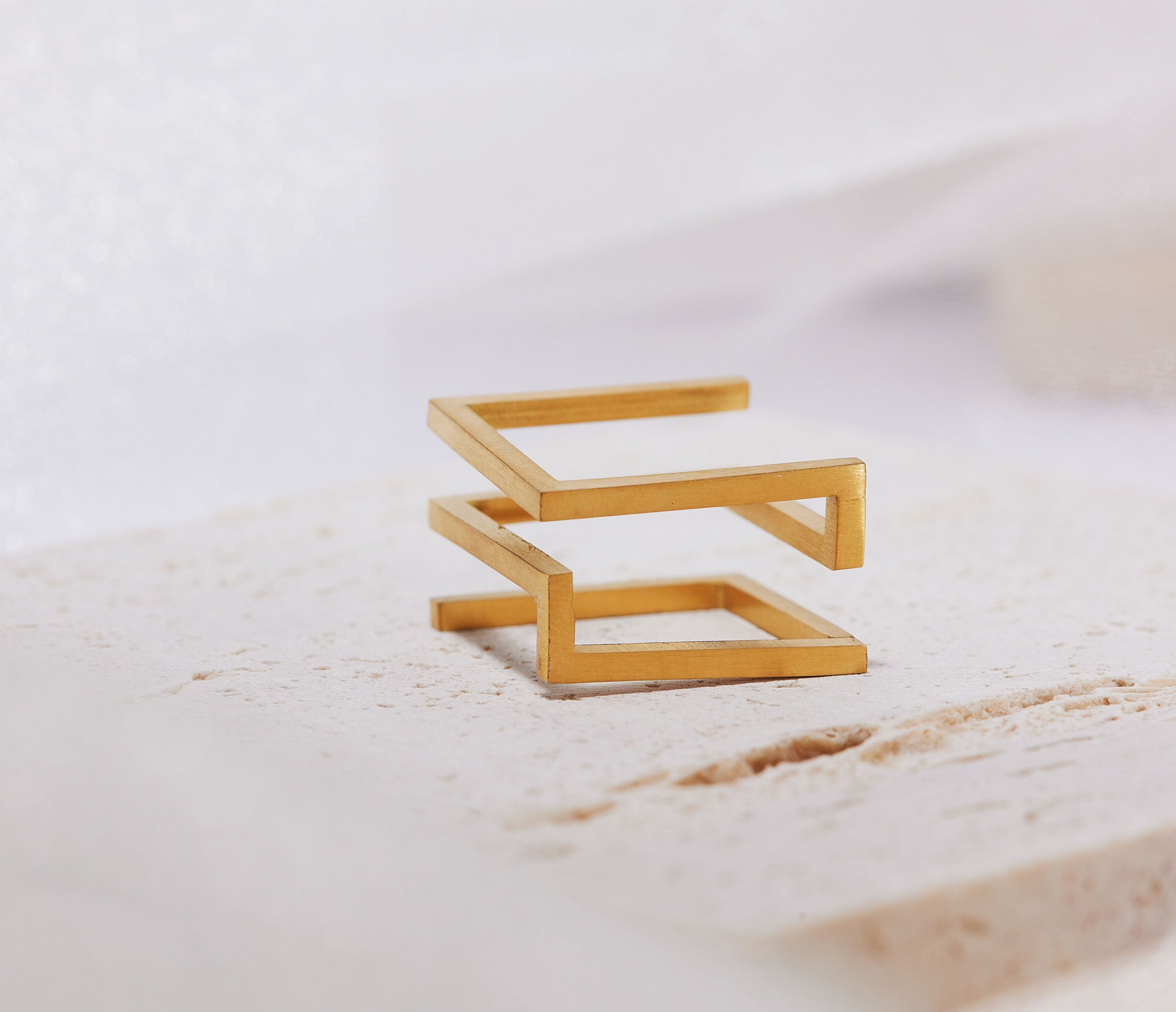 Gold geometric ring on a light marble surface