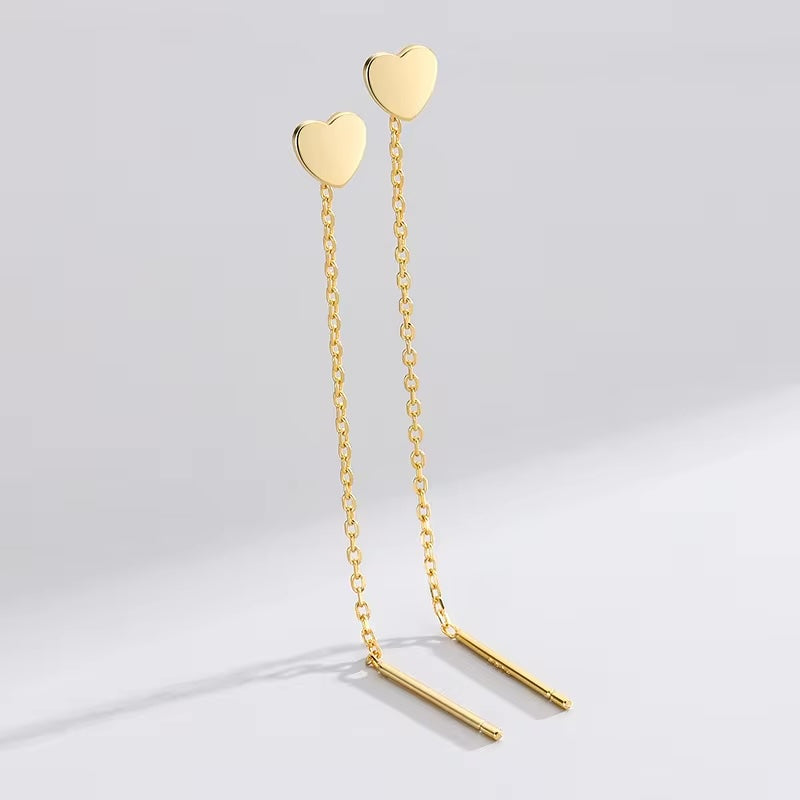 Gold heart-shaped earrings on a light gray background