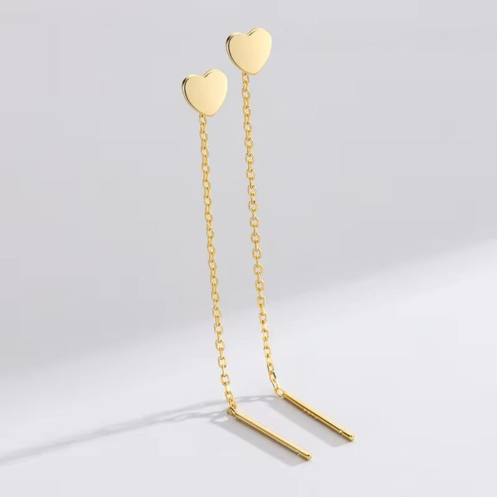 Gold heart-shaped earrings on a light gray background