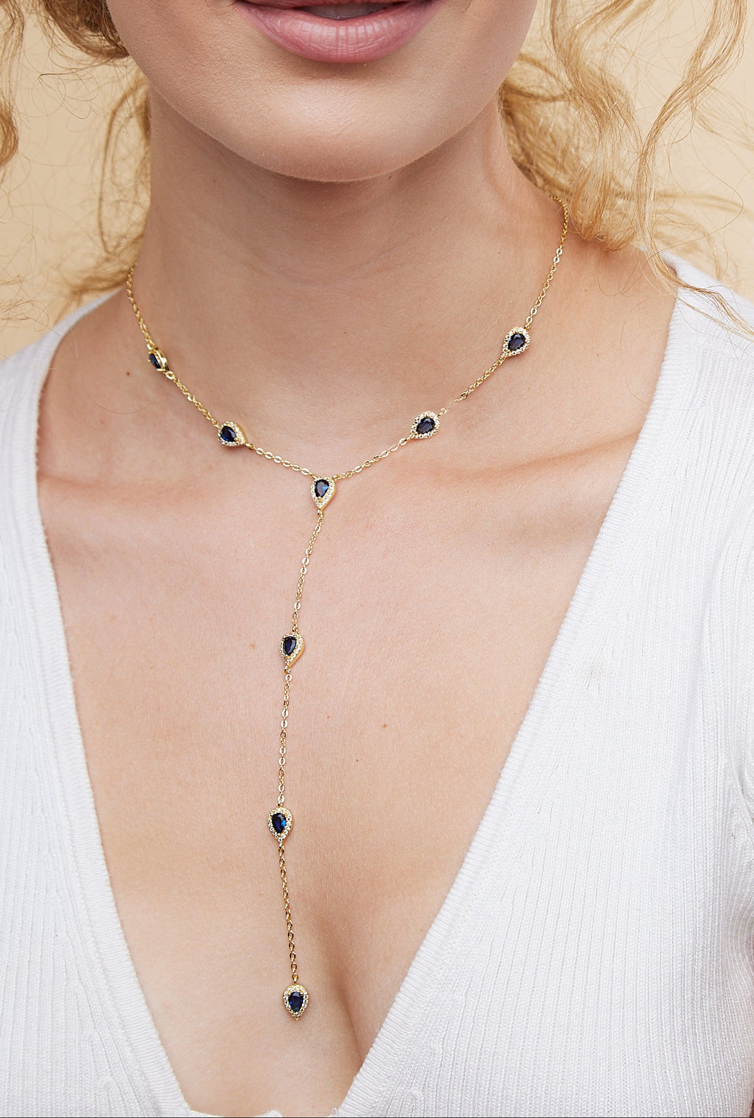 Woman wearing a delicate necklace with a beige background