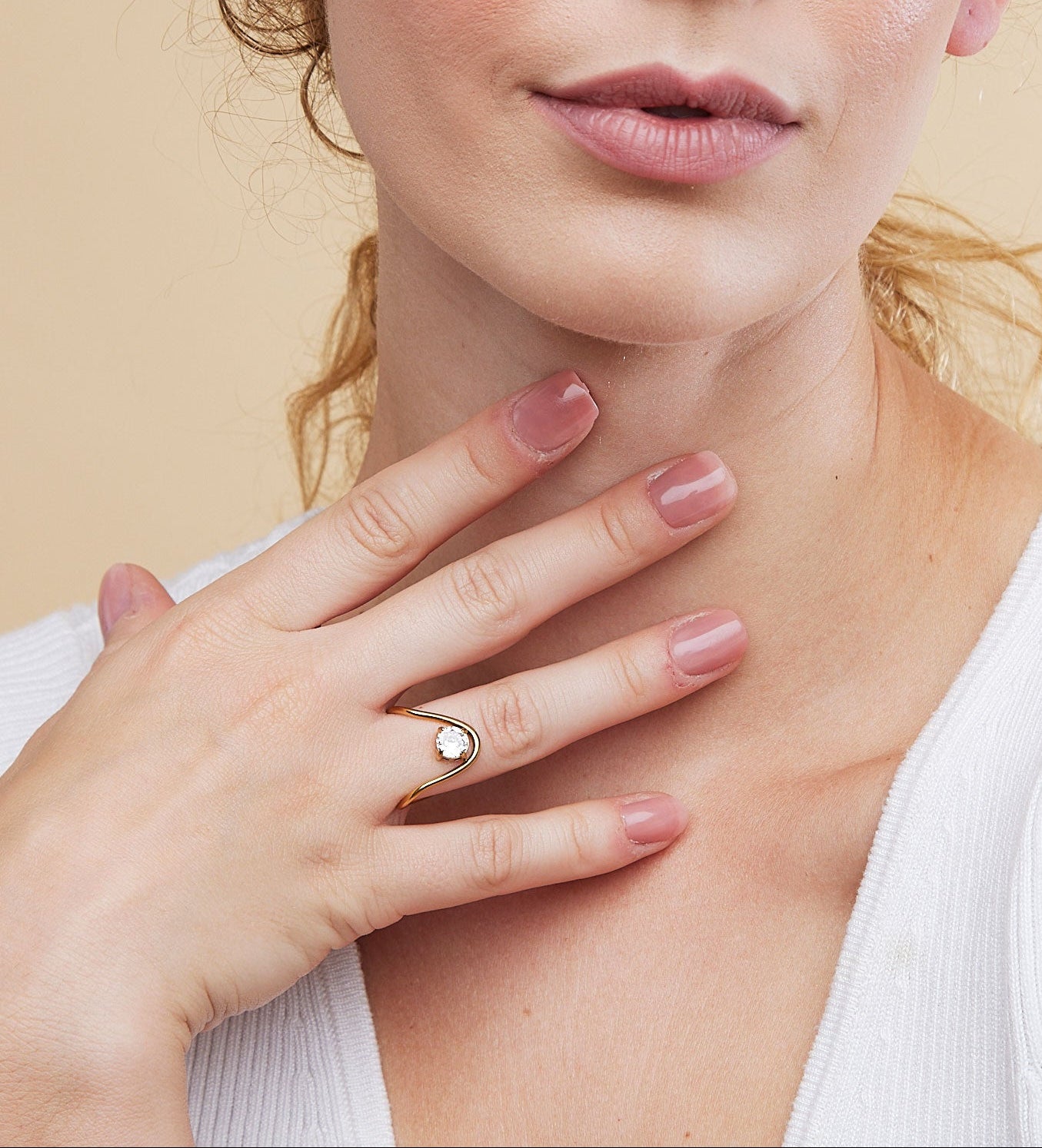 Woman wearing a ring on her finger against a beige background