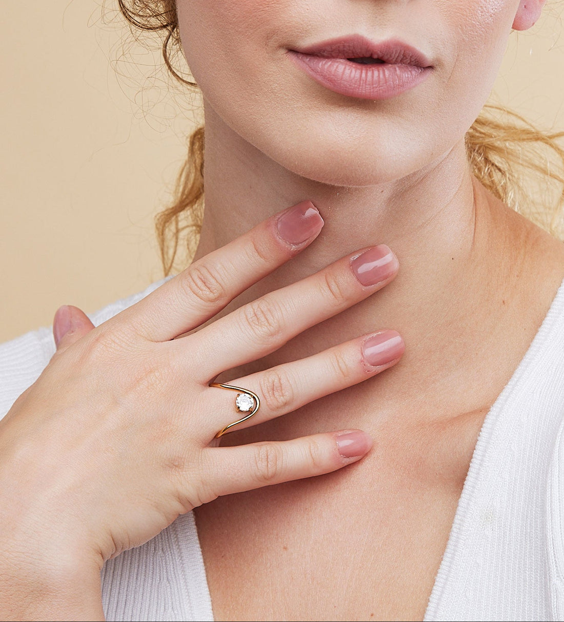 Woman wearing a ring on her finger against a beige background