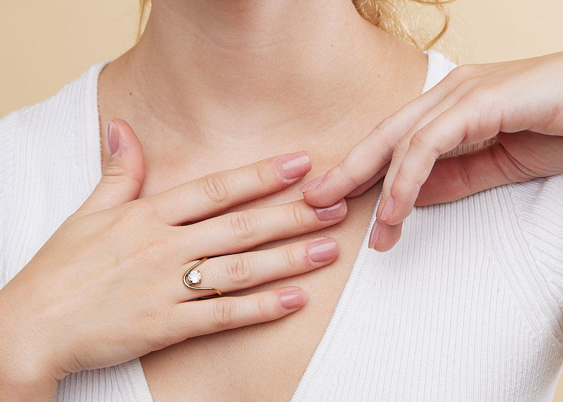 Woman wearing a delicate ring on a beige background