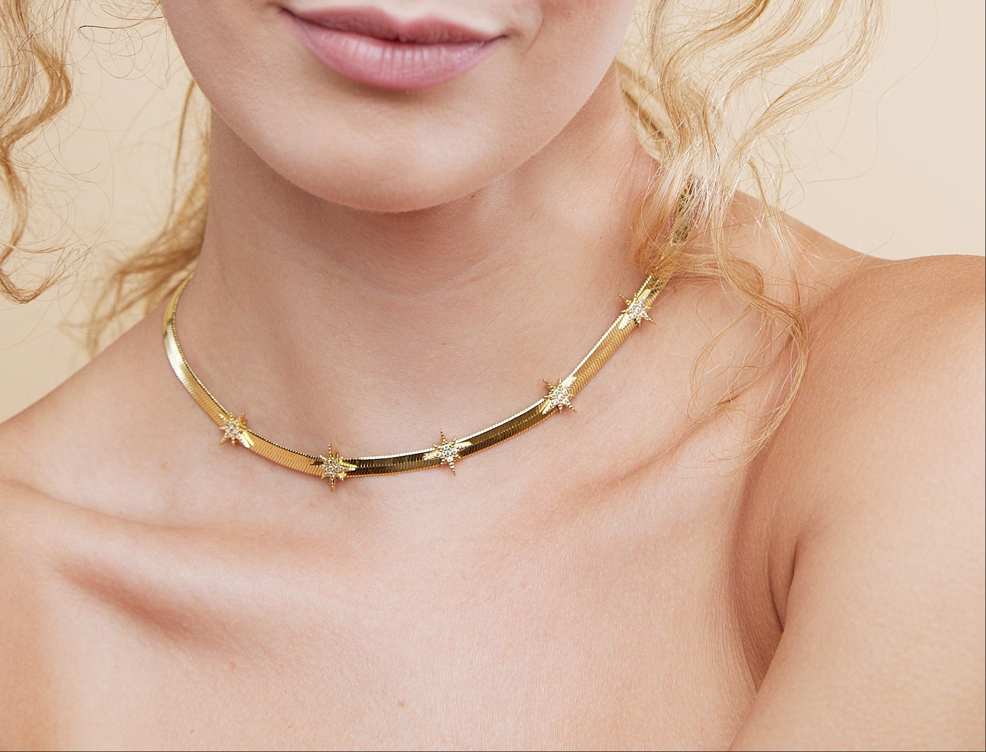 Woman wearing a gold necklace against a beige background